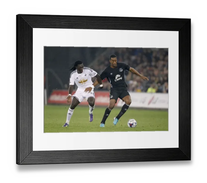 Framed Print : Intense Rivalry: Distin vs. Gomis Battle for Ball Supremacy in Swansea City vs. Everton's Capital One Cup Clash Framed Print : Intense Rivalry: Distin vs. Gomis Battle for Ball Supremacy in Swansea City vs. Everton's Capital One Cup Clash