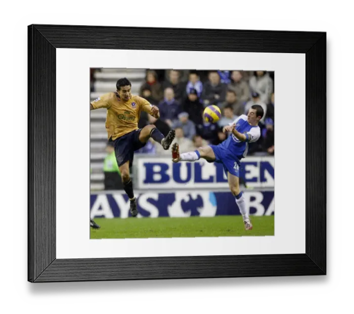 Framed Print : Wigan Athletics Baines challenges Evertons Cahill for the ball during their English Premier League