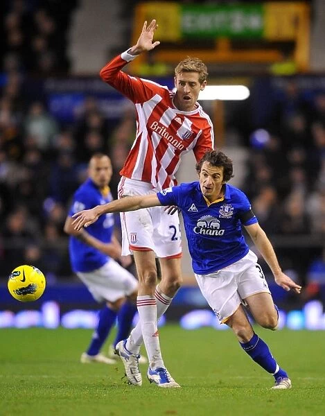 Intense Rivalry: Leighton Baines vs. Peter Crouch's Battle for the Ball at Goodison Park - Everton vs. Stoke City, Barclays Premier League (2011)