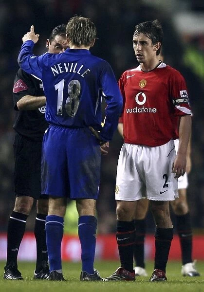 Phil Neville chats to the referee, watched by brother Gary