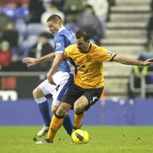 Intense Rivalry: McCarthy vs. Gibson's Battle for Ball at Wigan Athletic's DW Stadium (Everton vs. Wigan Athletic, BPL 2012) Intense Rivalry: McCarthy vs. Gibson's Battle for Ball at Wigan Athletic's DW Stadium (Everton vs. Wigan Athletic, BPL 2012)